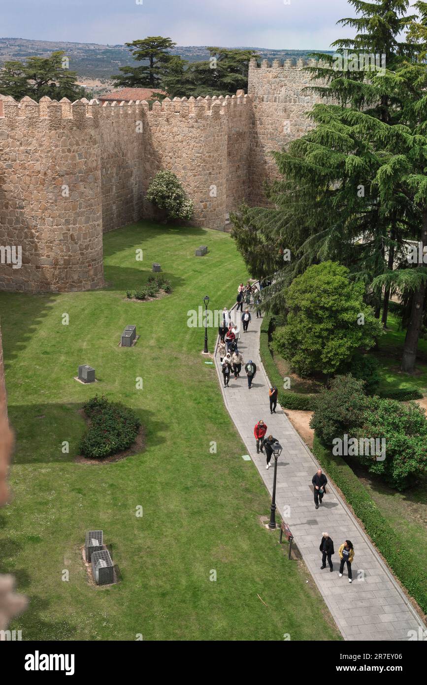 Le mura della città di Avila, vista delle persone che camminano lungo una sezione delle mura medievali ben conservate che circondano Avila, nella Spagna centrale. Foto Stock