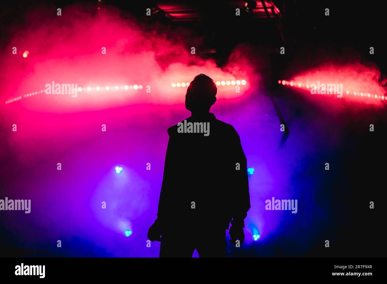 La silhouette di un uomo è circondata da un'atmosfera mitizzante di luci colorate e fumo, creando un aspetto etereo Foto Stock