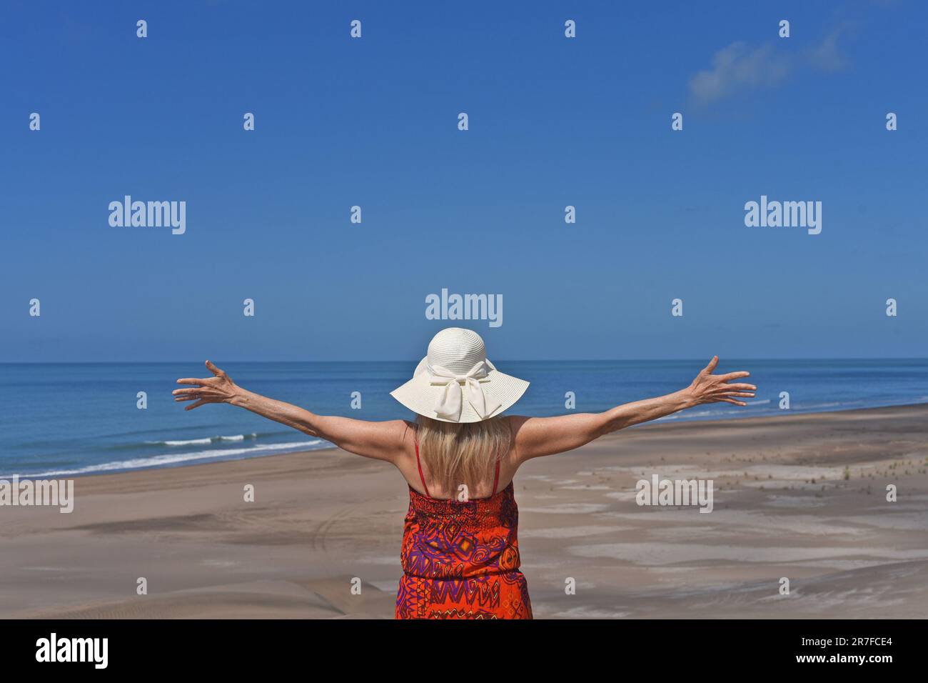 Donna con le braccia tese godendo le sue vacanze estive in spiaggia. Foto Stock
