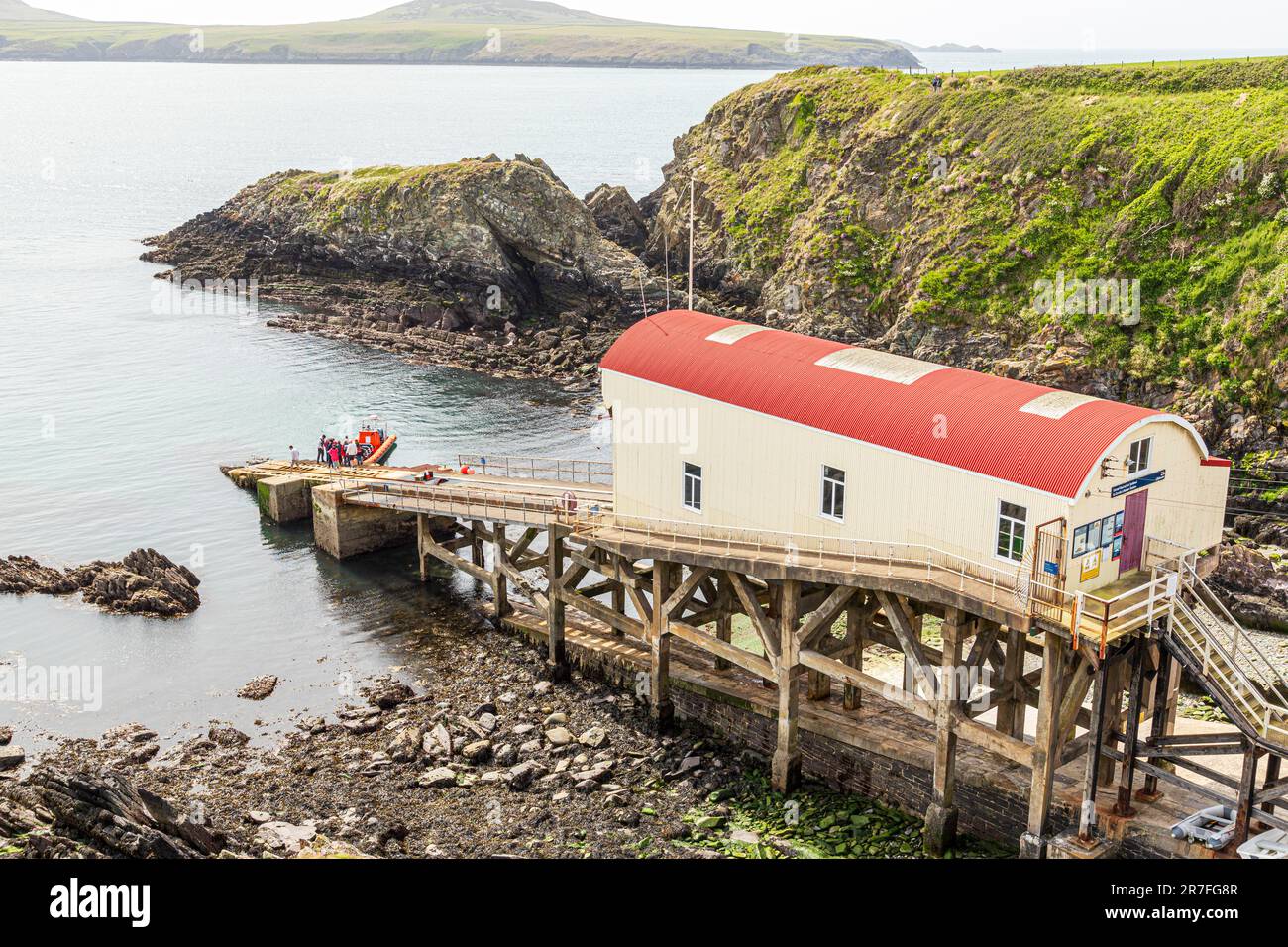 I turisti che partono per una gita in barca dalla vecchia stazione di scialuppa di salvataggio a St Justinesi nel Pembrokeshire Coast National Park, Galles, Regno Unito Foto Stock