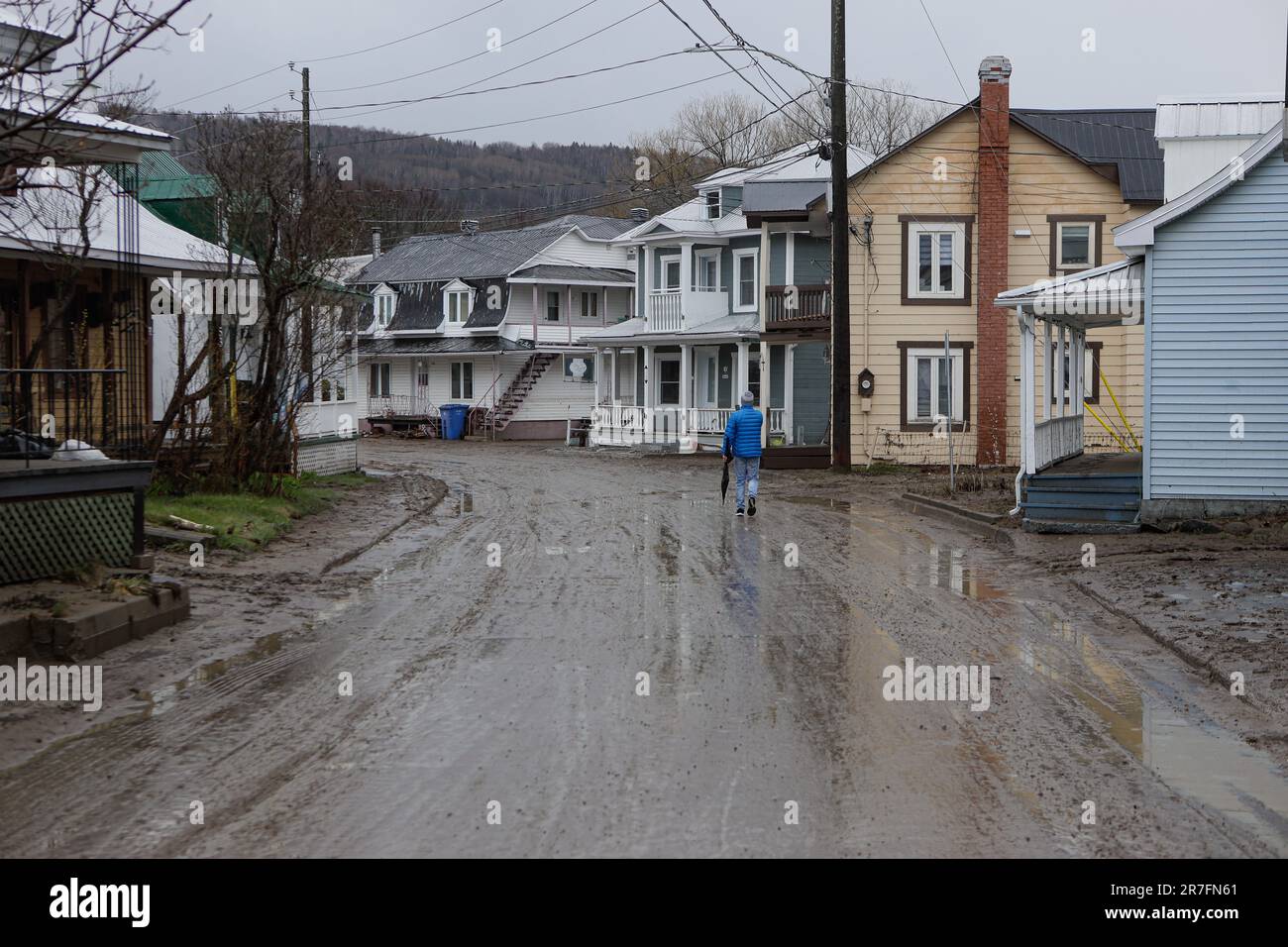 Un uomo cammina mentre riprende i danni su St-Joseph Street a Baie St-Paul il 2 maggio 2023. Le forti precipitazioni nella regione di Charlevoix hanno portato a trabocchioni di fiumi nella Baie St-Paul e nelle aree circostanti, con conseguenti alluvioni e danni significativi a residenze, aziende e infrastrutture. Foto Stock