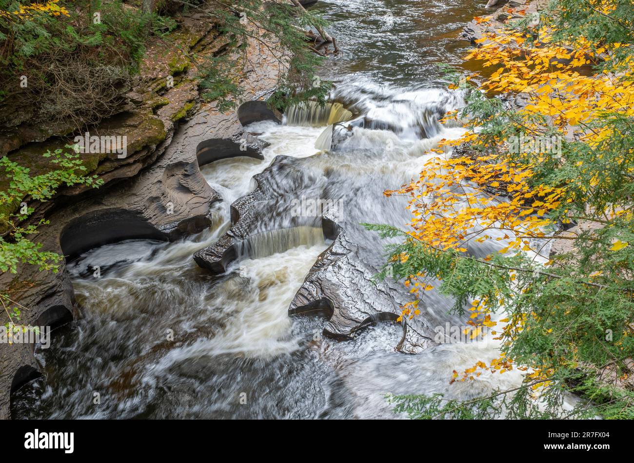 Il fiume Presque Isle della penisola superiore del Michigan è un paese delle meraviglie d'autunno tra il fogliame mutevole e le numerose cascate e il rame c Foto Stock