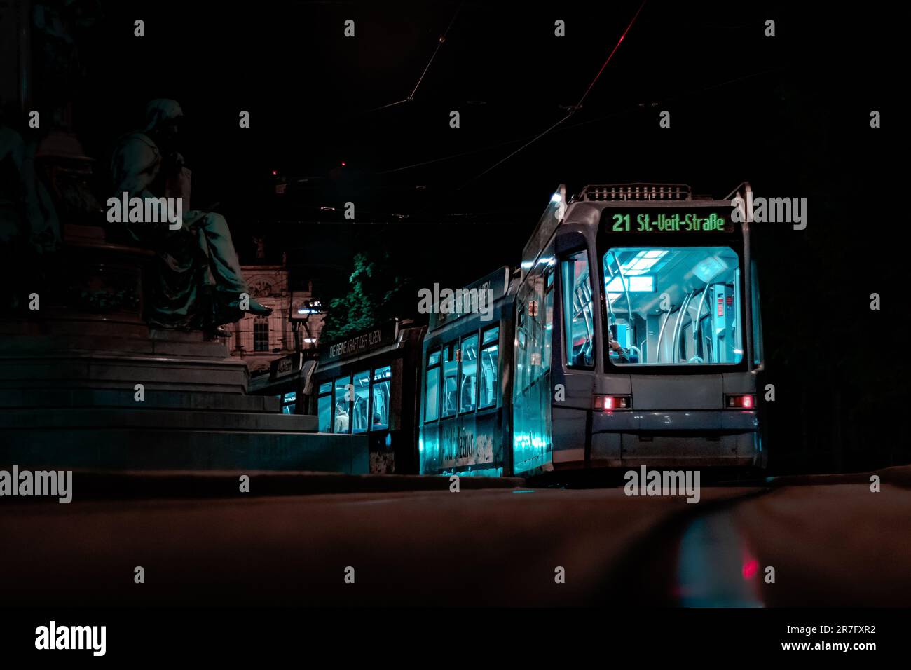 Un autobus cittadino illuminato di notte, con diversi passeggeri all'interno Foto Stock