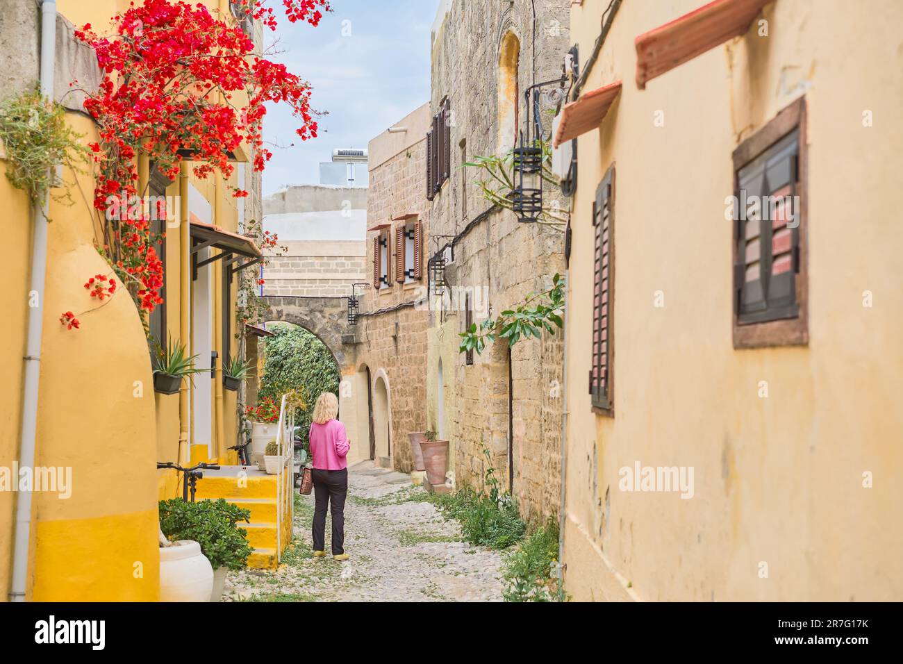 Camminando per le strade del centro storico di Rodi lontano dai luoghi turistici, una donna adulta è a piedi lungo la strada, un viaggio alla popolare p Foto Stock