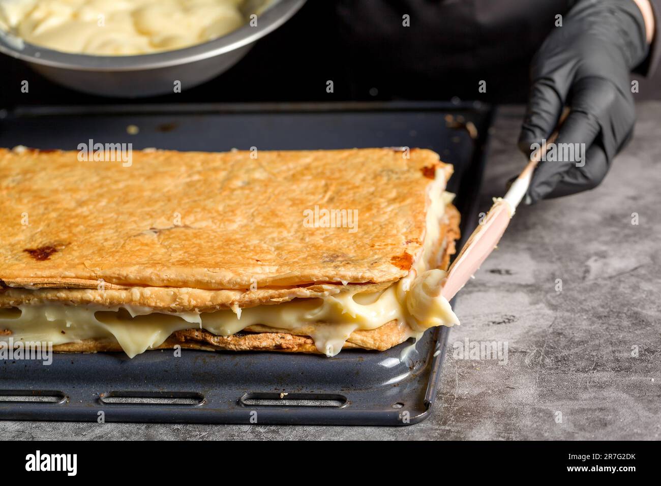 Processo di preparazione di una torta Napoleone con semi di papavero e ciliegie. Primo piano Foto Stock