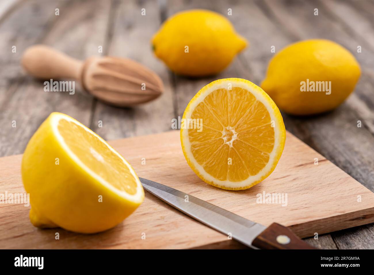 Limone fresco tagliato a metà con coltello sul tagliere di legno. Messa a fuoco selettiva. Foto Stock