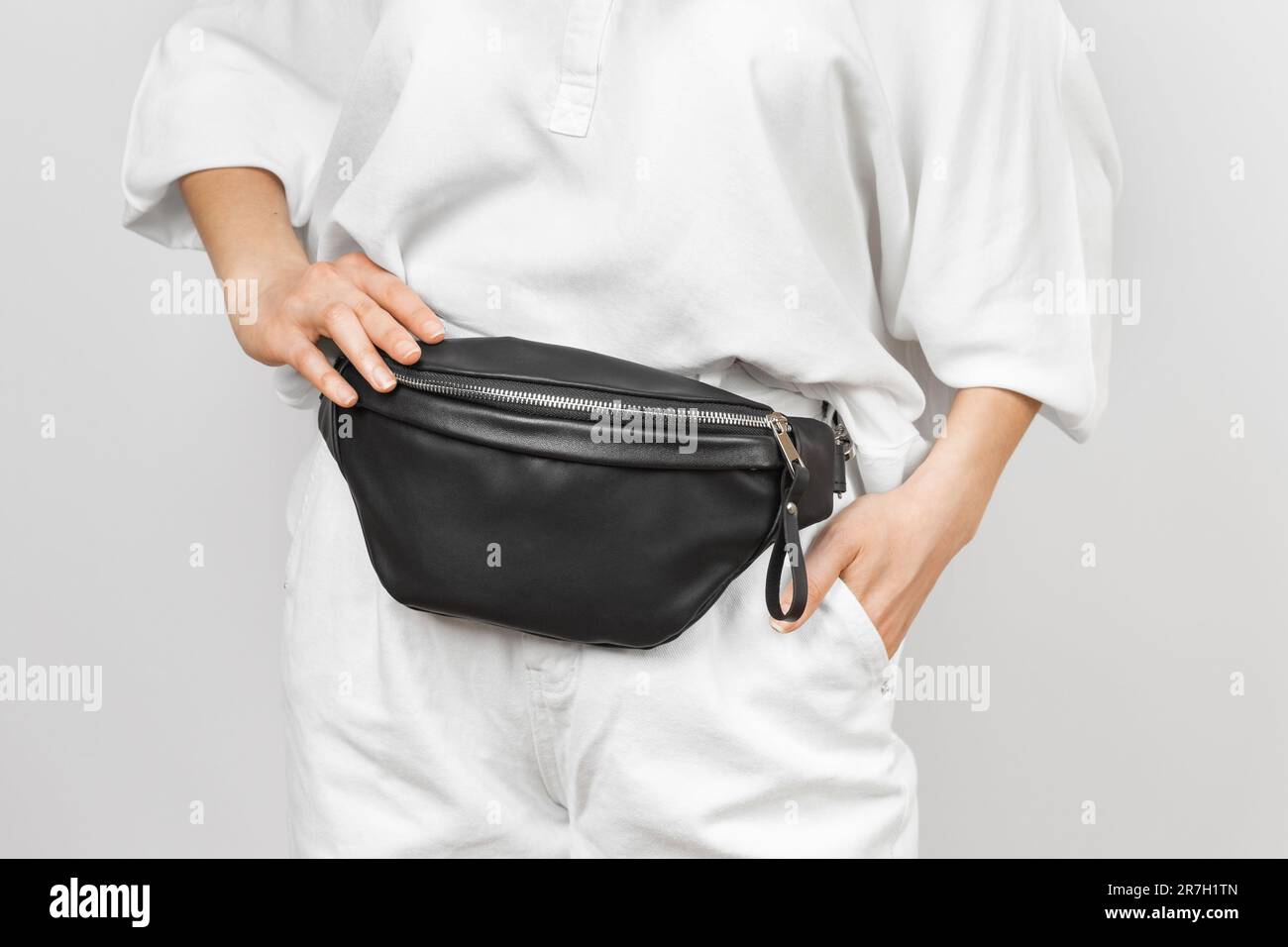 Borsa in vita in pelle nera per donna con jeans e camicia bianchi. Accessori in pelle fatti a mano Foto Stock