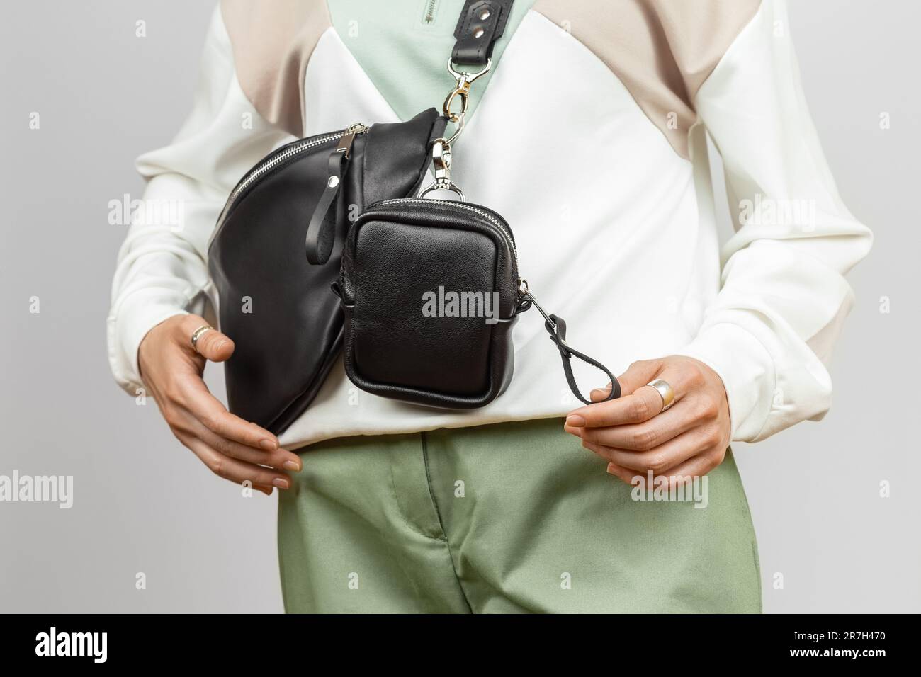 Piccoli accessori in pelle per riporre chiavi, sigarette o auricolari attaccati alla tracolla in Fanny Pack in vera pelle nera. Modello femmina Foto Stock