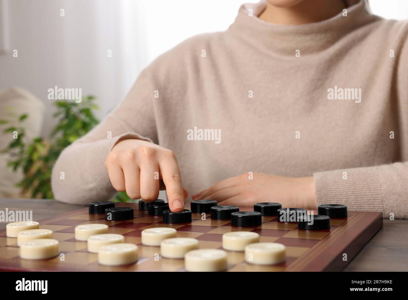 Pedine. Donna che pensa alla prossima mossa a tavolo in camera, primo piano Foto Stock