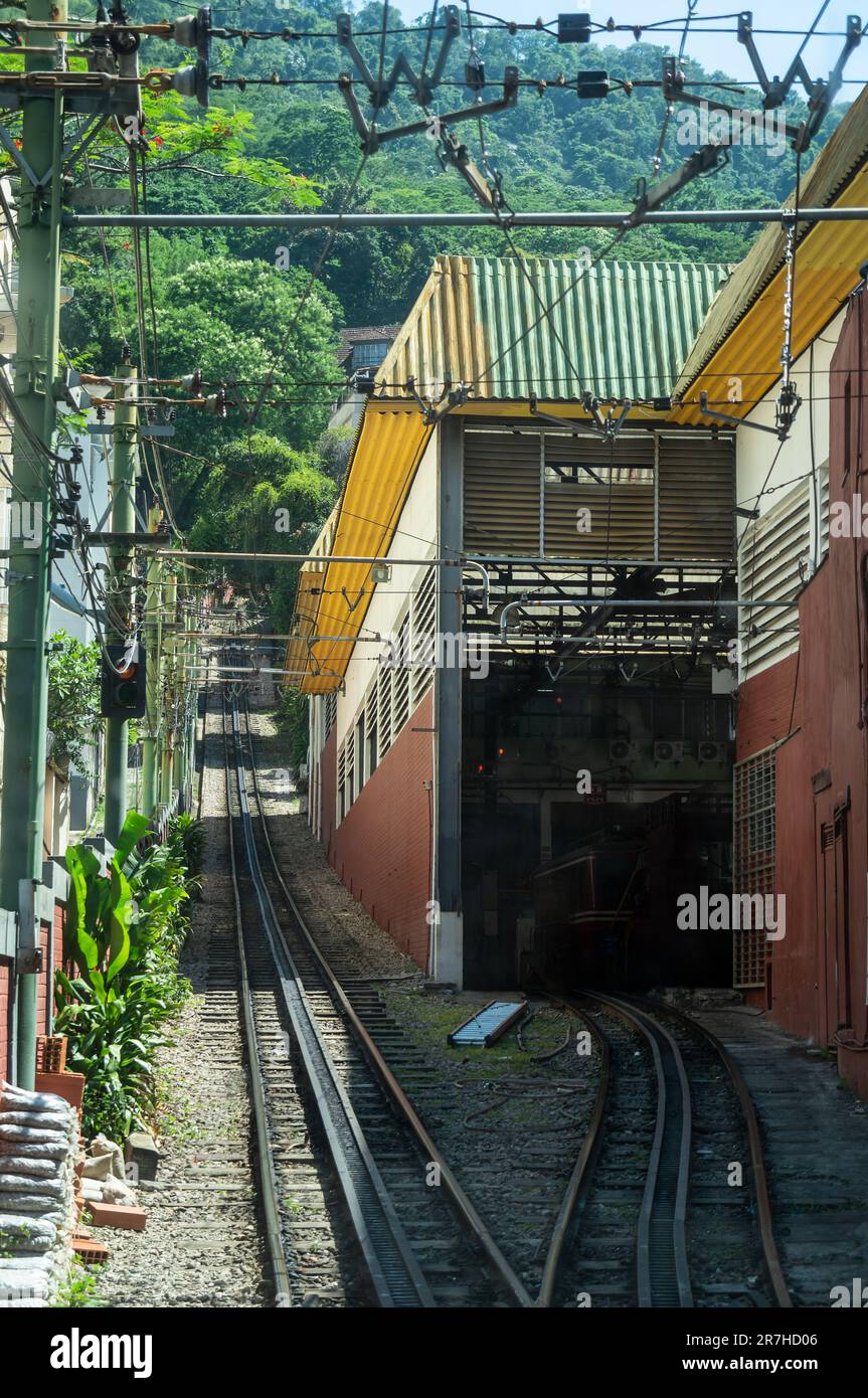 Vista dei binari ferroviari Corcovado rack Railway e del deposito di manutenzione sulla destra vicino alla stazione Cosme Velho sotto il cielo azzurro e soleggiato d'estate. Foto Stock