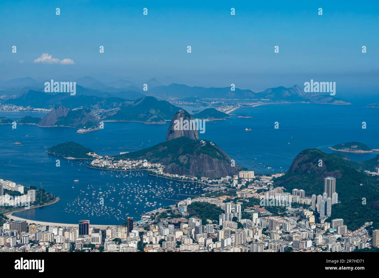 Vista lontana del Pan di zucchero e dei monumenti naturali della collina di Urca con il quartiere di Botafogo sottostante come visto dalla cima del monte Corcovado durante la giornata estiva. Foto Stock