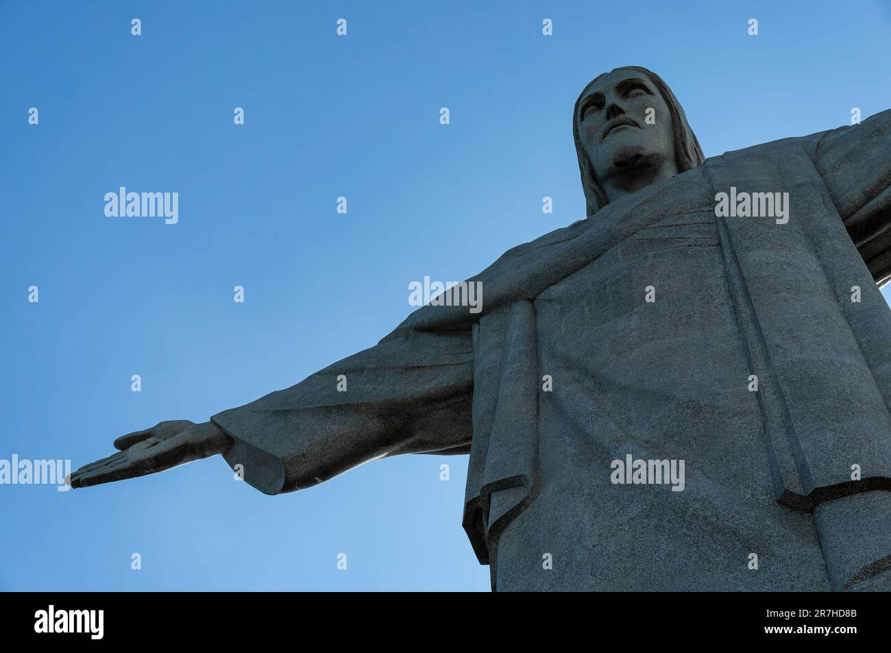 Guardando verso l'alto il lato anteriore destro della statua del Cristo Redentore situata sulla cima del monte Corcovado sotto il cielo azzurro e soleggiato d'estate. Foto Stock