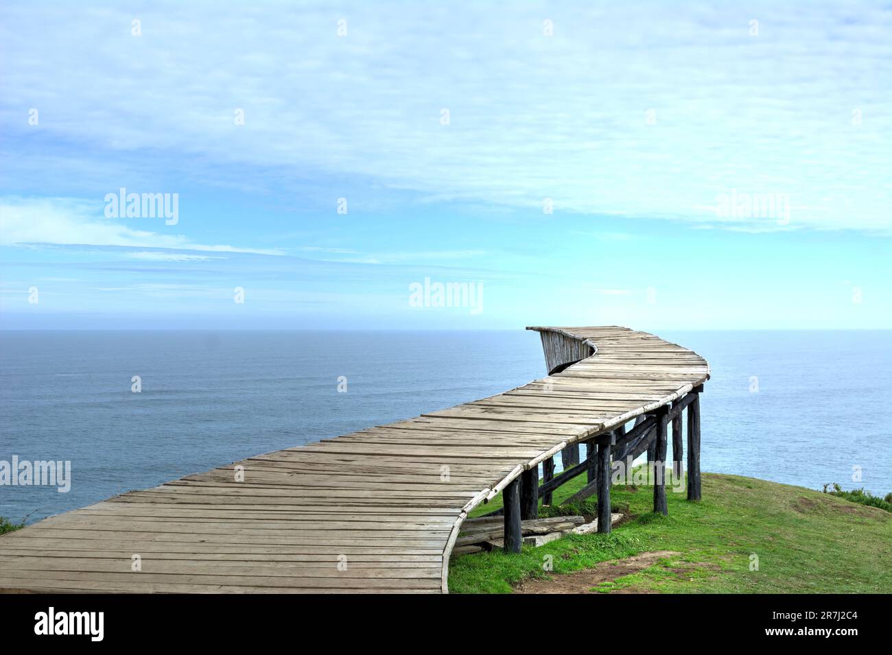Lungo ponte pedonale in legno (il "Dock of Souls" di Chiloé) di fronte all'oceano in una giornata limpida Foto Stock