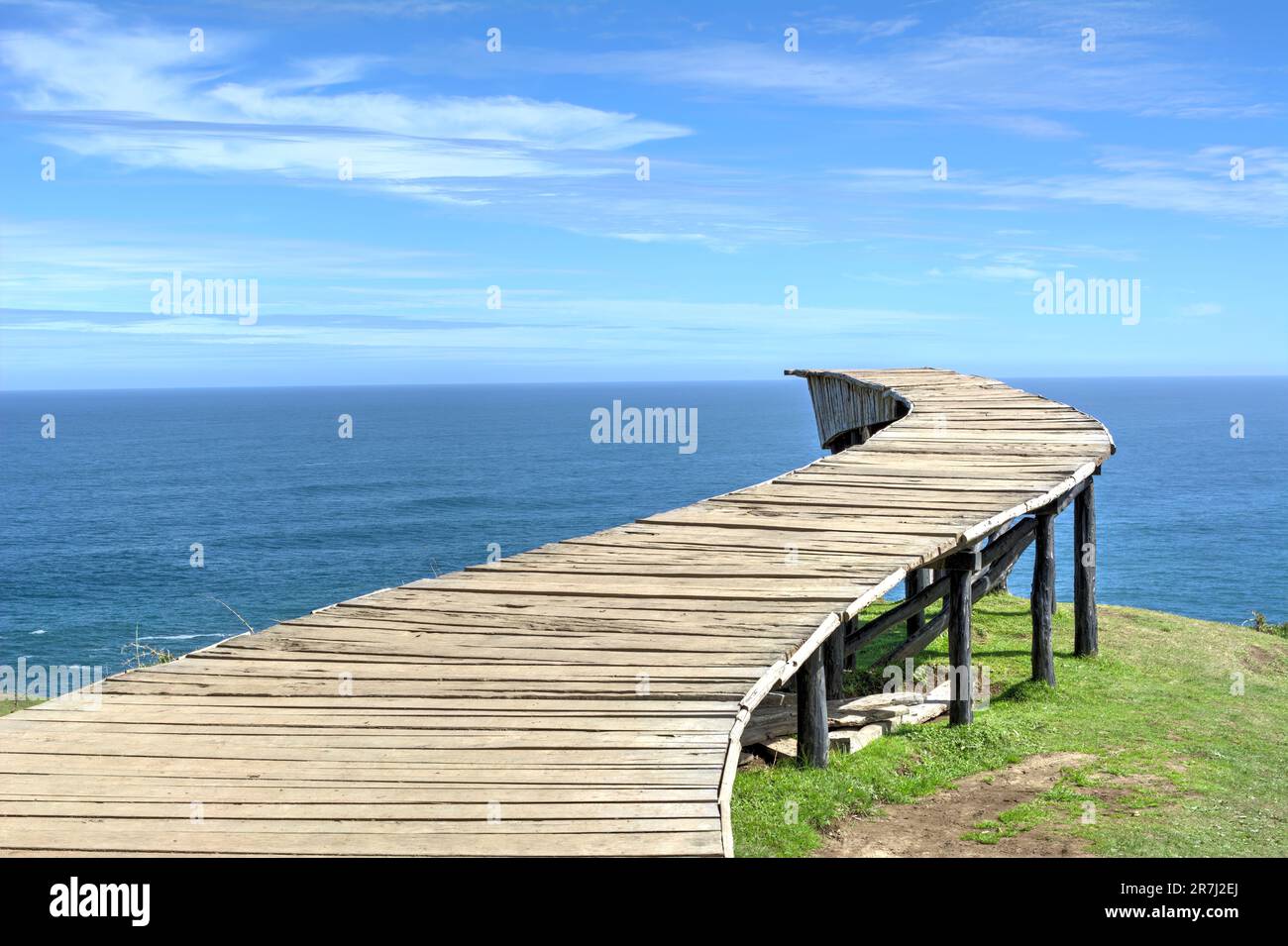 Lungo ponte pedonale in legno (il "Dock of Souls" di Chiloé) di fronte all'oceano in una giornata limpida Foto Stock