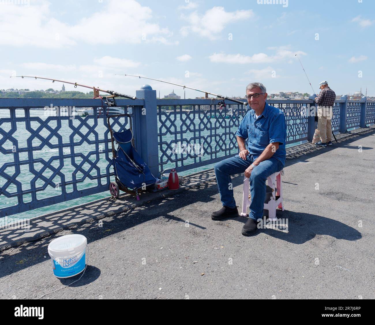 L'anziano isherman con gli occhiali sul ponte Galata si siede su una sedia per fare una pausa, Istanbul, Turchia Foto Stock