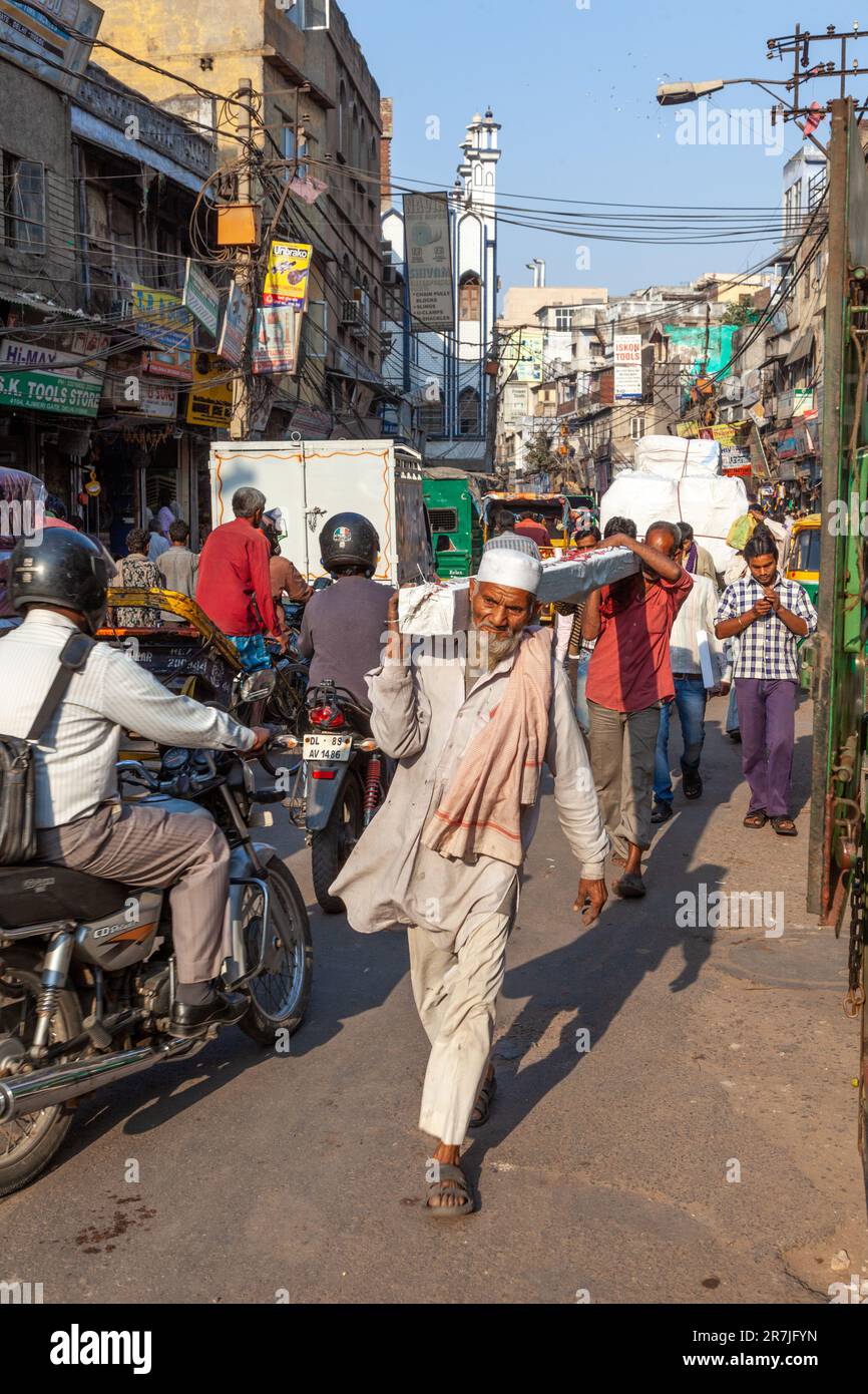 Nuova Delhi, India - 17 novembre 2011: vita di strada al più antico mercato Chandni Chowk nella vecchia Delhi. Le persone che portavano il goodsed la loro spalla al Meena Bazaar Foto Stock