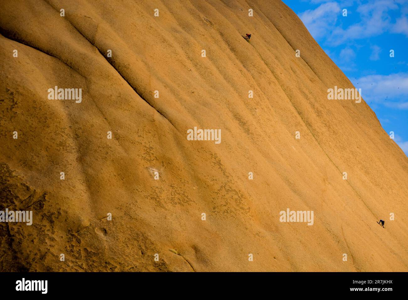 Due arrampicatori femminili lavorano là in alto la faccia di arenaria. Cielo blu che sale sotto il sole africano. Foto Stock