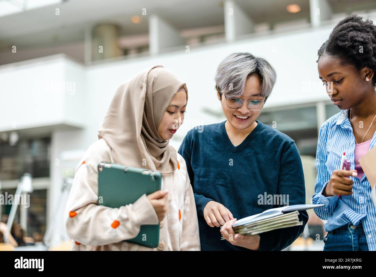 Gruppo di studenti multietnici che discutono in una biblioteca Foto Stock