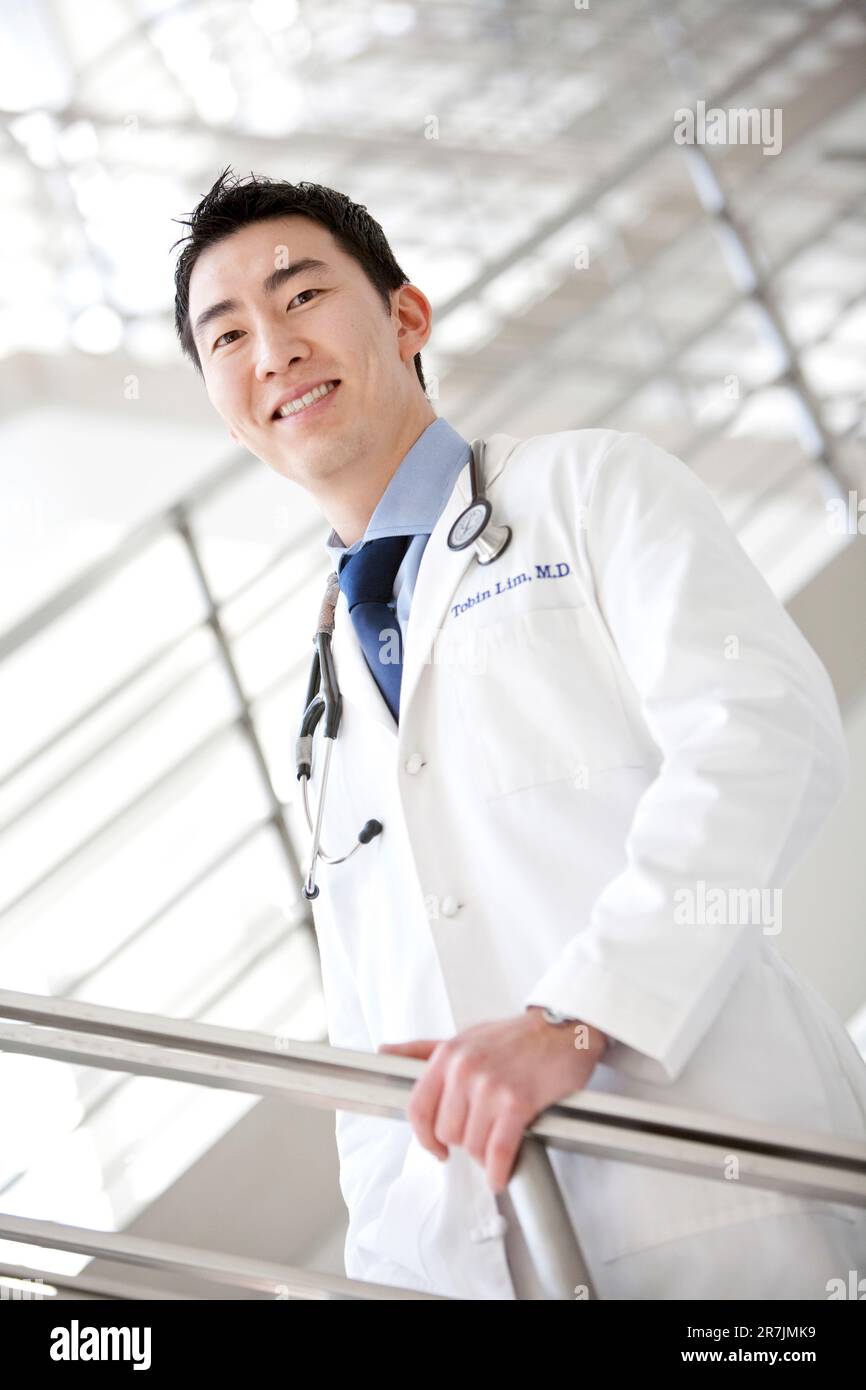 Un ritratto di un medico maschile sorridente in un camice bianco da laboratorio con uno stetoscopio intorno al collo. Foto Stock