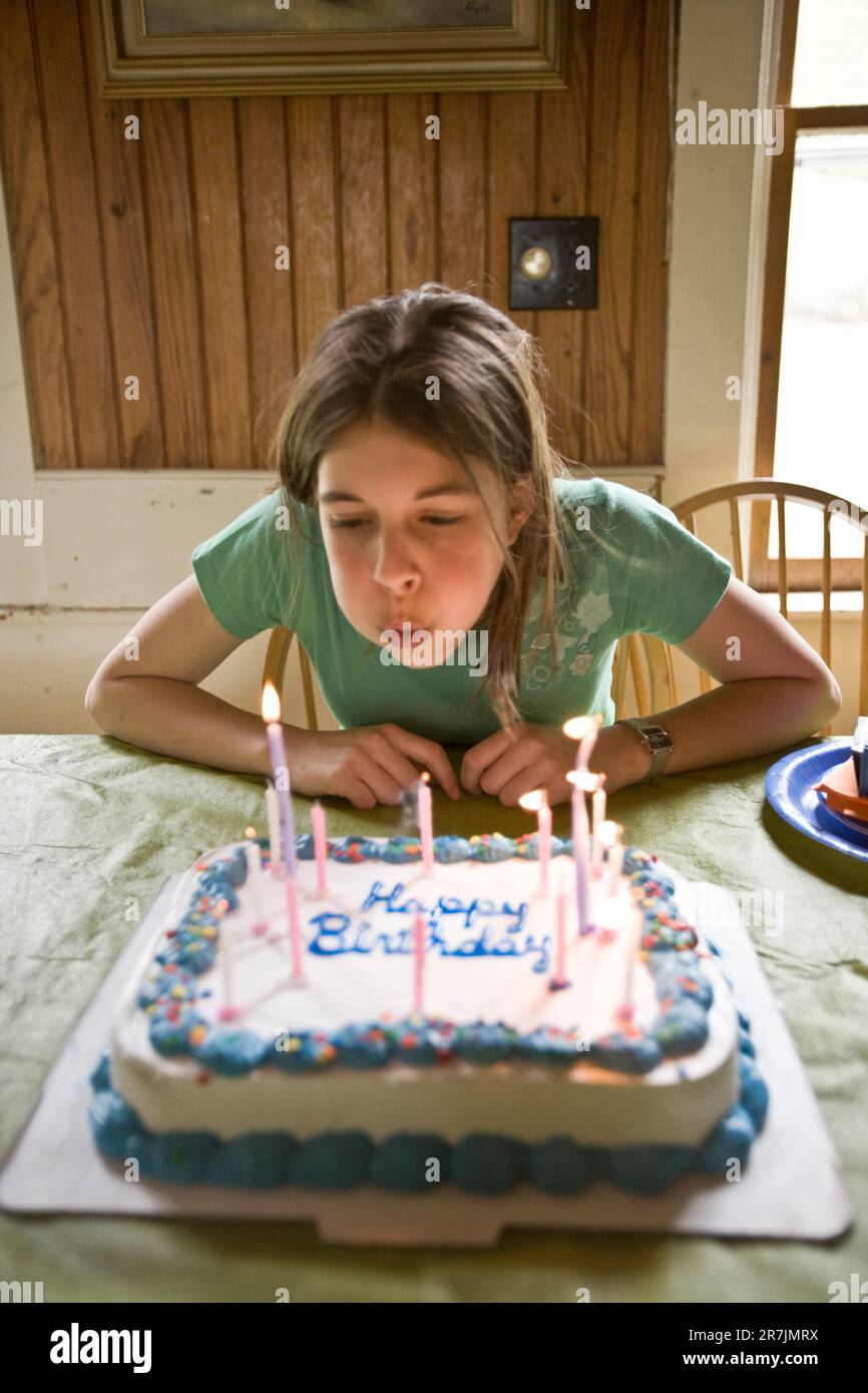 Una giovane ragazza soffia fuori le candele di compleanno su una torta decorativa nella sua casa nel Maine. Foto Stock