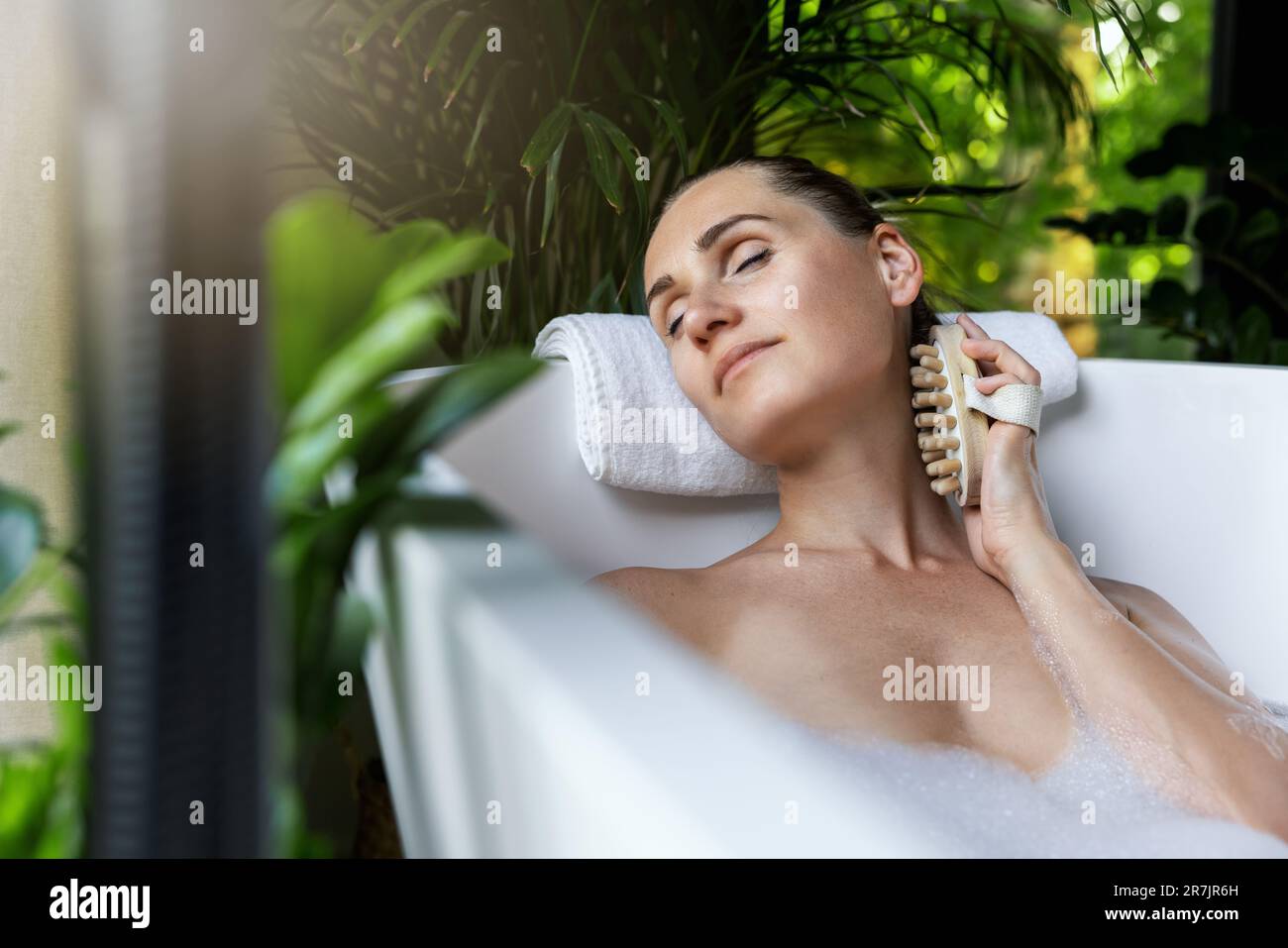 donna che gode di una vasca termale benessere con spazzola per massaggio corpo Foto Stock