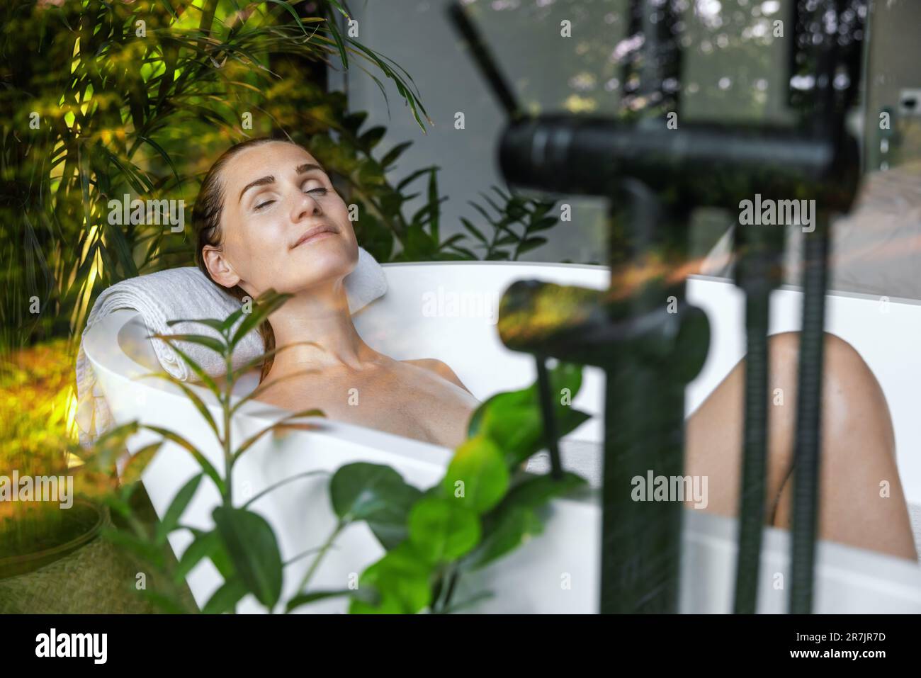 donna che si rilassa in bagno con piante verdi. cura della pelle, hotel benessere spa, salute del metallo Foto Stock