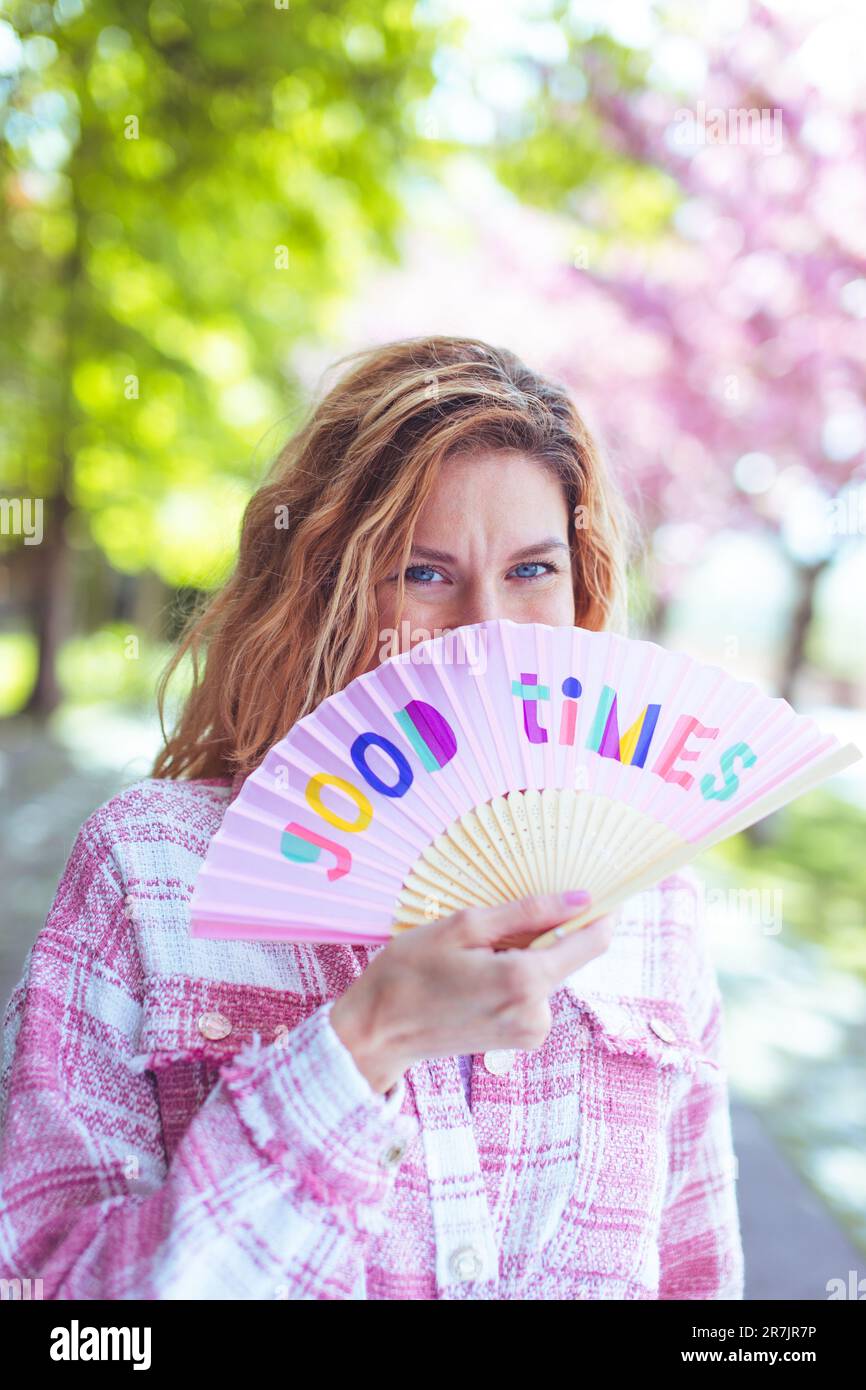 Felice donna nascosto sorriso dietro i buoni tempi fan in primavera Foto Stock