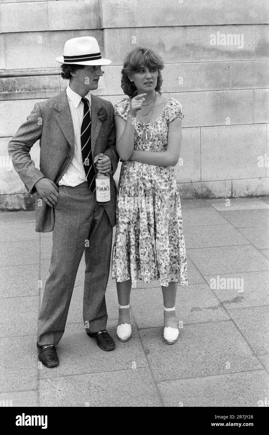 Bottiglia di Pimms No1 in mano un vecchio Harrovian e la sua ragazza si dirigono all'annuale partita di cricket Eton V Harrow al Lords Cricket Ground, Londra. Sembra elegante con un cappello di paglia di Panama, e Prince of Wales vestito e mocassini. Indossa un abito floreale Laura Ashleyesque e espadrillas. St Johns Wood, Londra, Inghilterra giugno 1978 1970s UK HOMER SYKES Foto Stock