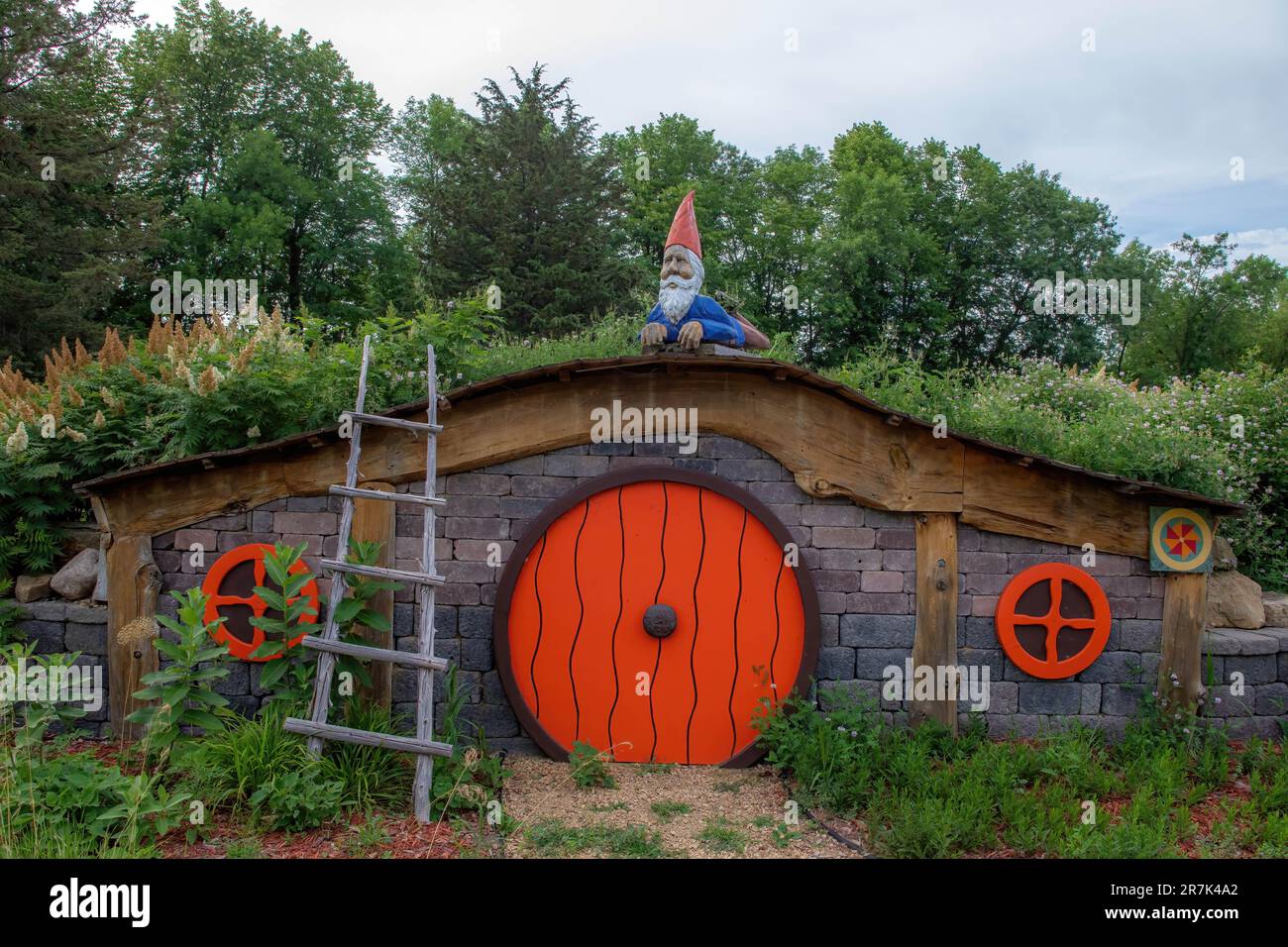 Gnomo scandinavo decorativo che si posa sulla cima di una casa tipo hobbit con una scala a Sven Factory Outlet Store a Chisago City, Minnesota USA. Foto Stock