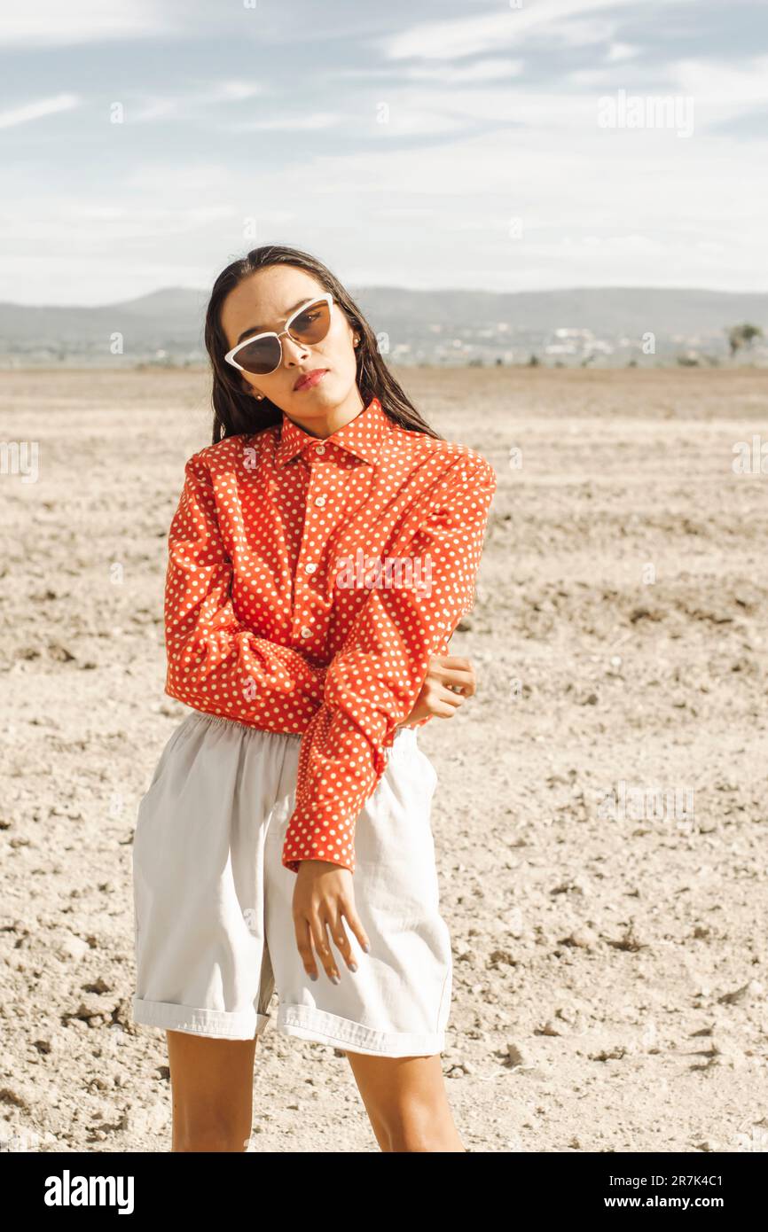 Giovane donna alla moda che indossa occhiali da sole nel deserto Foto Stock