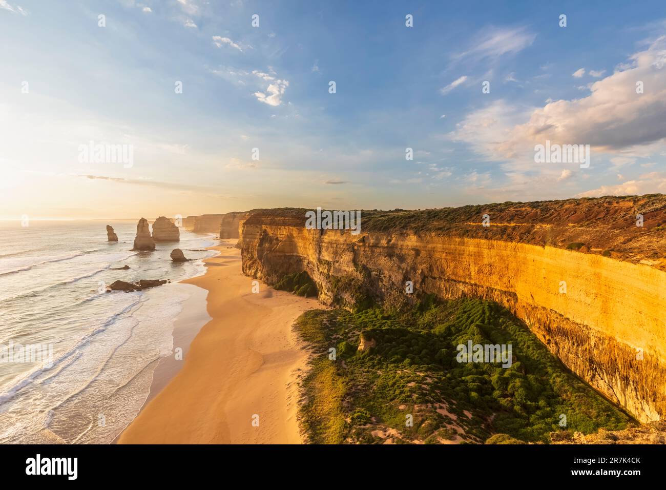 Australia, Victoria, Vista della spiaggia sabbiosa nel Parco Nazionale di Port Campbell al tramonto con dodici Apostoli sullo sfondo Foto Stock