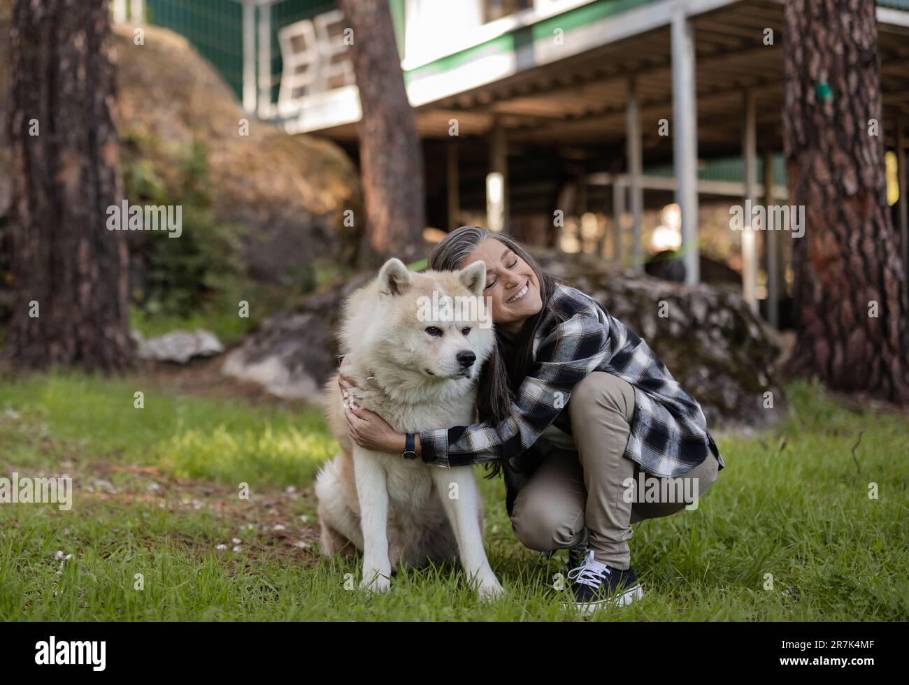 Donna matura che abbraccia il cane in giardino Foto Stock