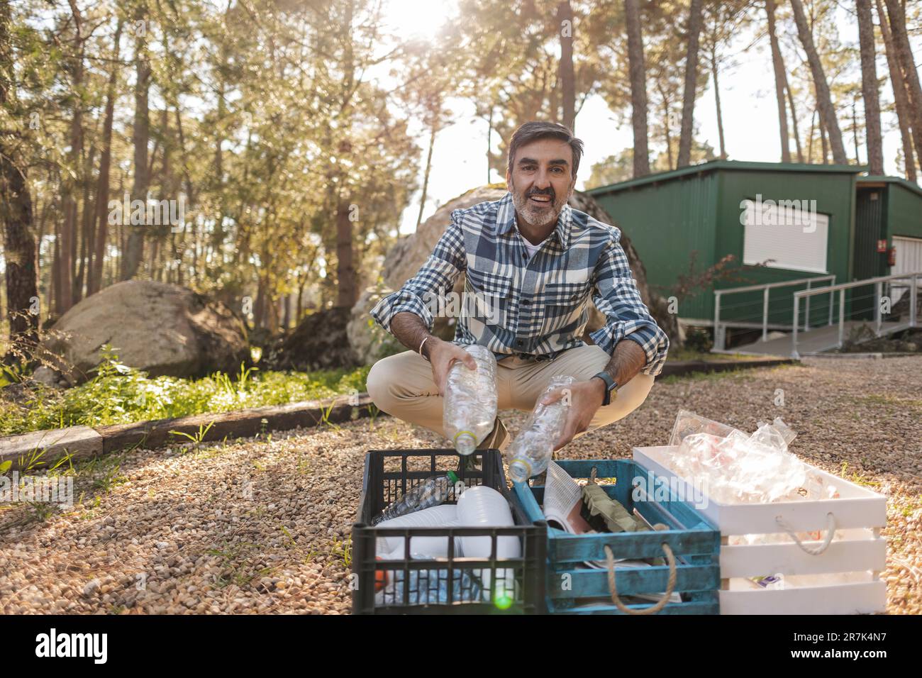 Uomo maturo che separa i rifiuti in casse in giardino Foto Stock