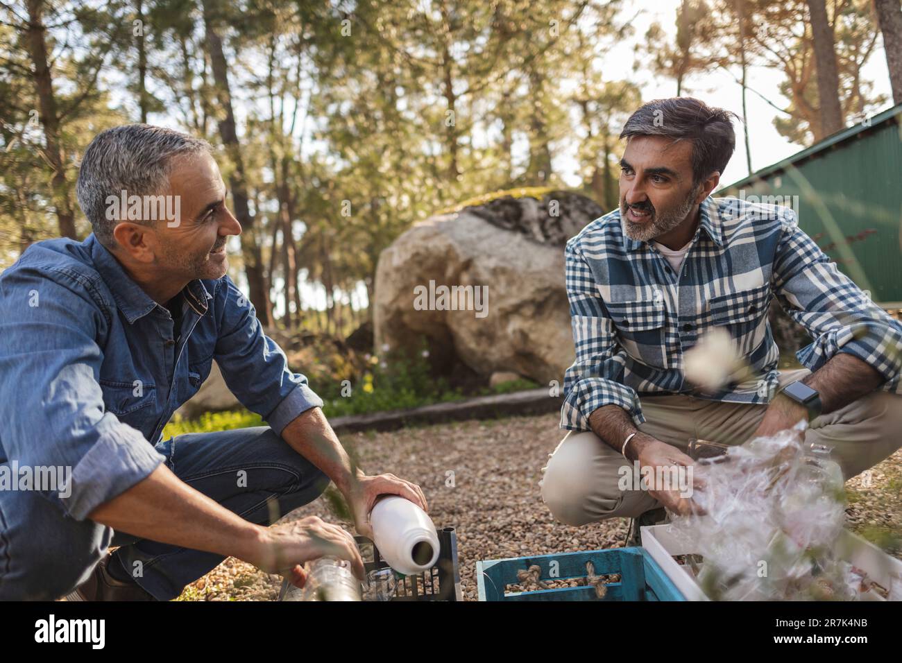 Maturo che parla in uomini di giardino che separano i rifiuti in casse Foto Stock