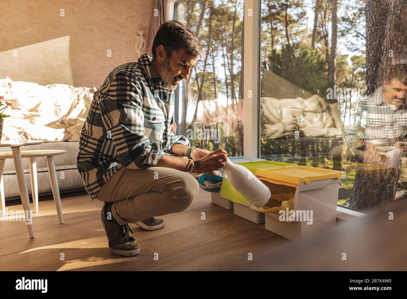 Uomo che mette il flacone di plastica nel contenitore di separazione dei rifiuti Foto Stock