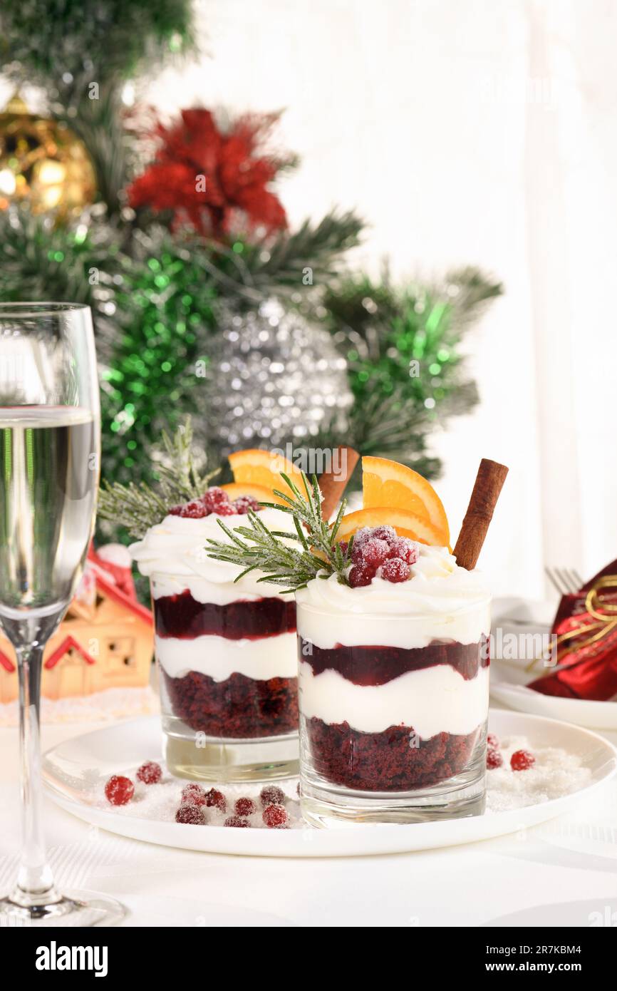 Dessert natalizio al miramisù con mascarpone e panna montata, biscotti al cioccolato sbriciolati e confettura di mirtilli, guarniti con fette di arancia, lattina Foto Stock