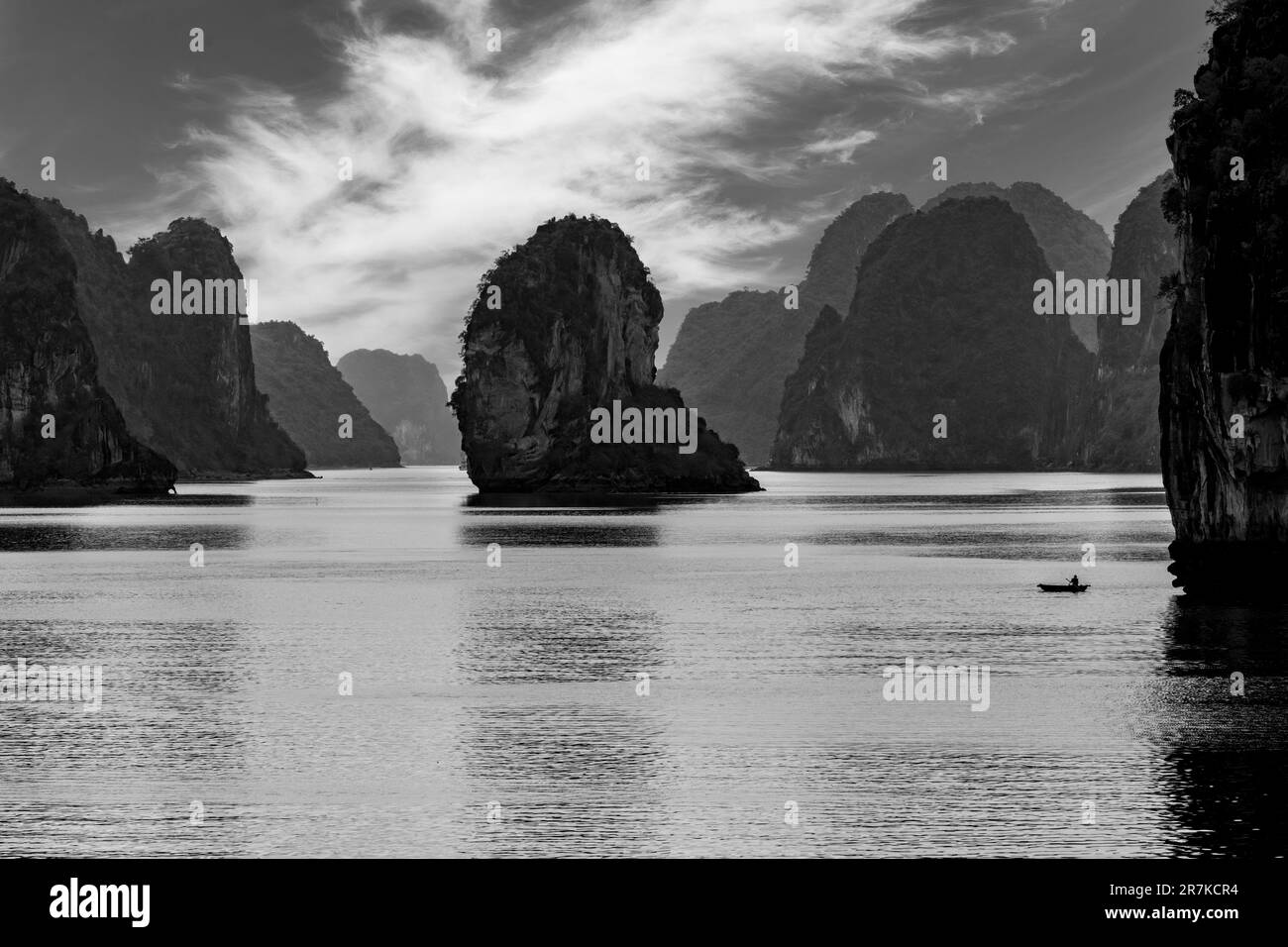Vista panoramica sulle acque della Baia di ha Long, Vietnam con caratteristici carsici e isole di pietra calcarea monolitiche e una piccola barca singola con pescatore Foto Stock