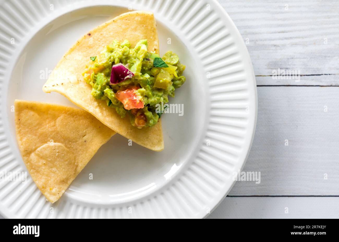 Un piatto con tortillas di mais croccanti sormontato da guacamole fatte in casa. Foto Stock