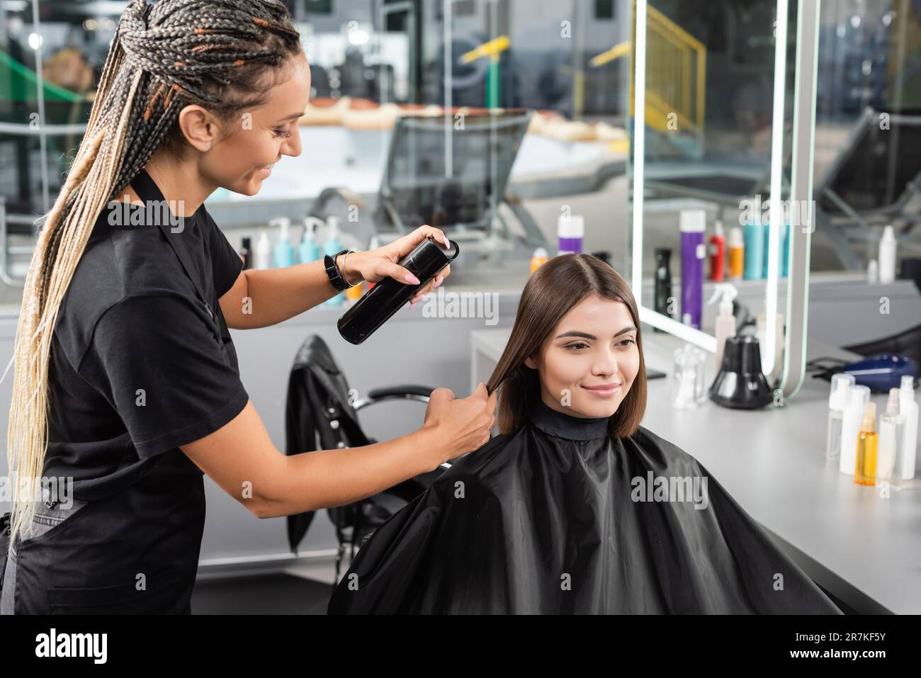 salone di bellezza, spray per capelli, parrucchiere felice con trecce styling capelli della cliente femminile, bruna donna felice con capelli corti, salone di bellezza, capelli vo Foto Stock