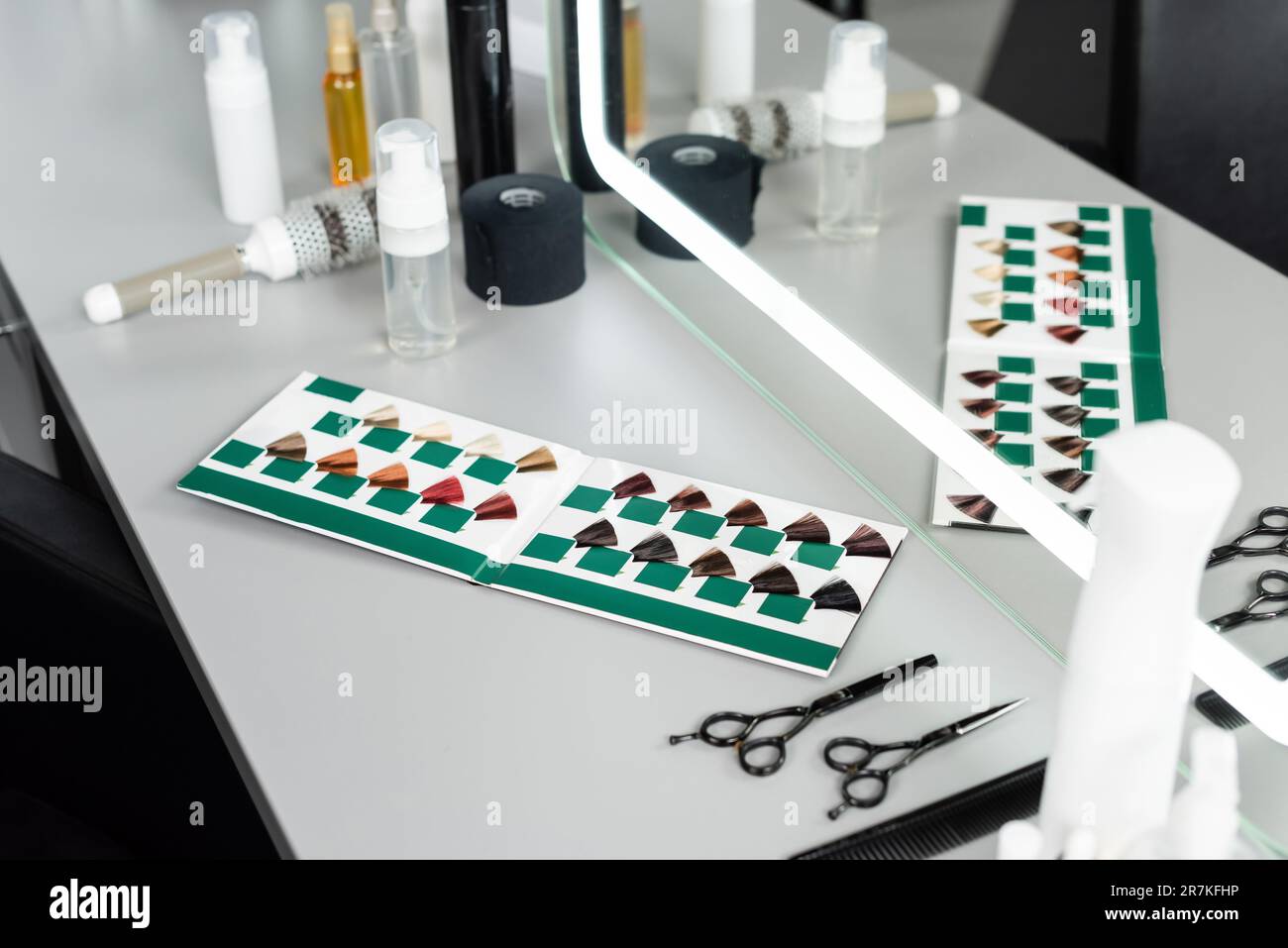 strumenti per il taglio dei capelli, forbici per parrucchieri, biberon, olio per capelli, pettine, spazzola rotonda, libro di tavolozza di capelli vicino specchio in salone di bellezza, accessori per capelli, bellezza Foto Stock