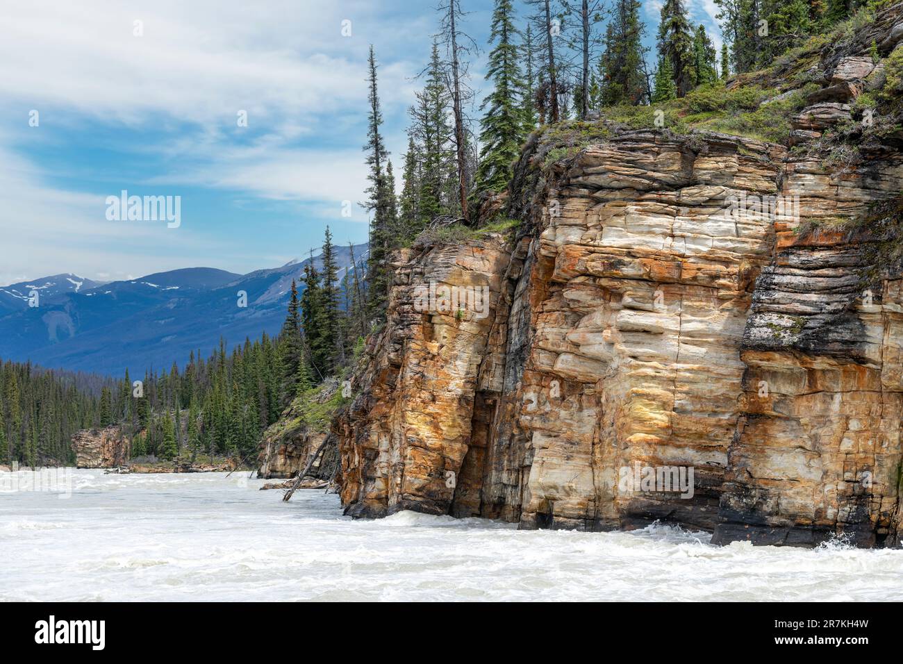 Vista sul fiume Athabasca che scorre dalle vicine cascate Athabasca, dal Jasper National Park, AB, Canada, con sulla riva del fiume grandi forme di roccia colorata Foto Stock