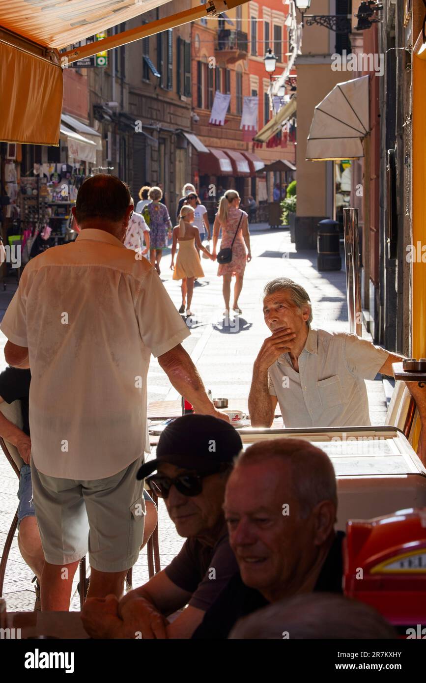 Gli uomini si sono seduti a parlare al bar sulla tipica strada di Rapallo, Rapallo, Liguria, Italia Foto Stock