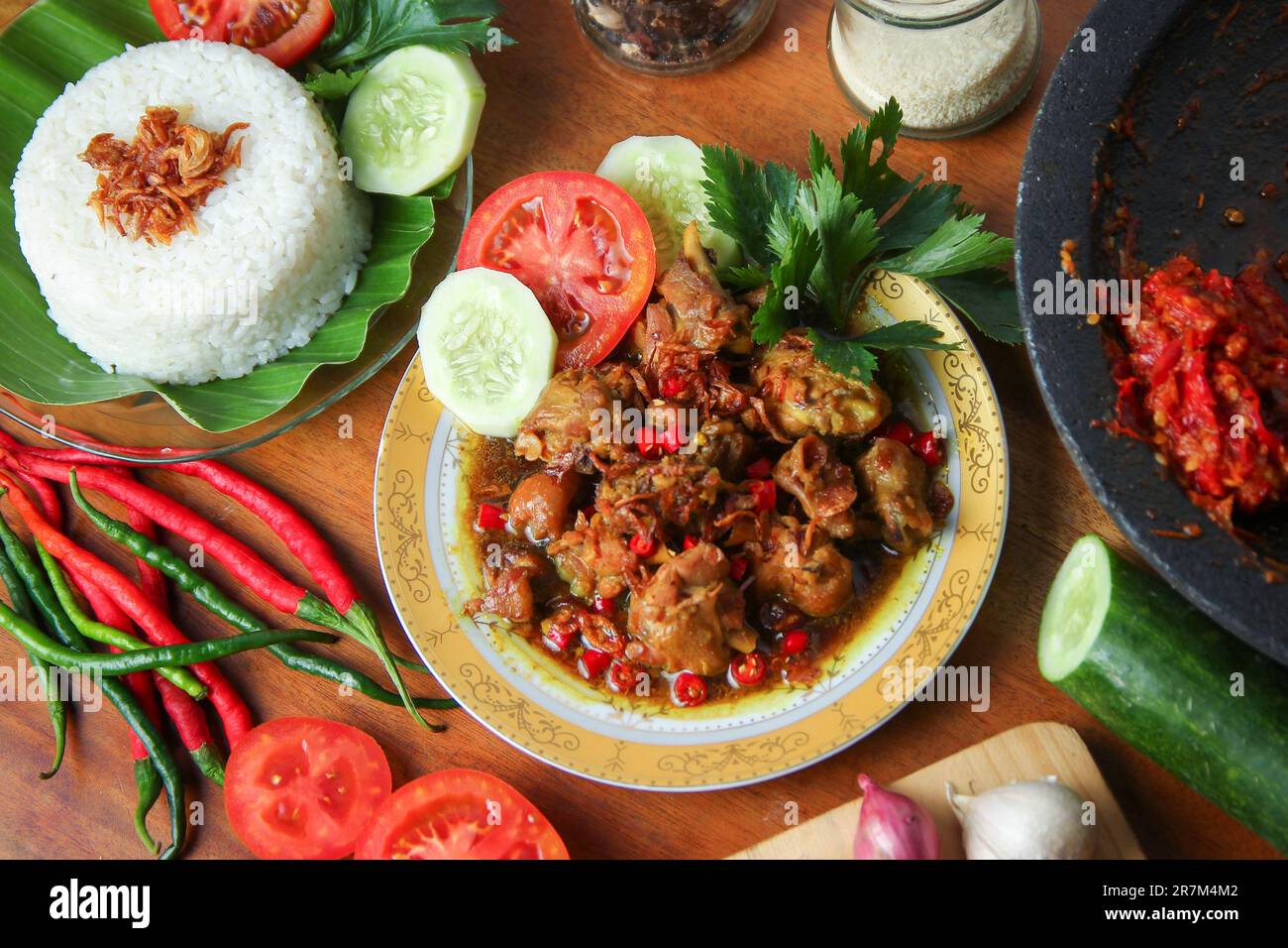 Cucina indonesiana con foto gastronomiche. Pollo rica-rica con pomodoro, cetriolo, sedano, riso. Pollo speziato in umido con peperoncino sul tavolo. Cucina di strada Foto Stock