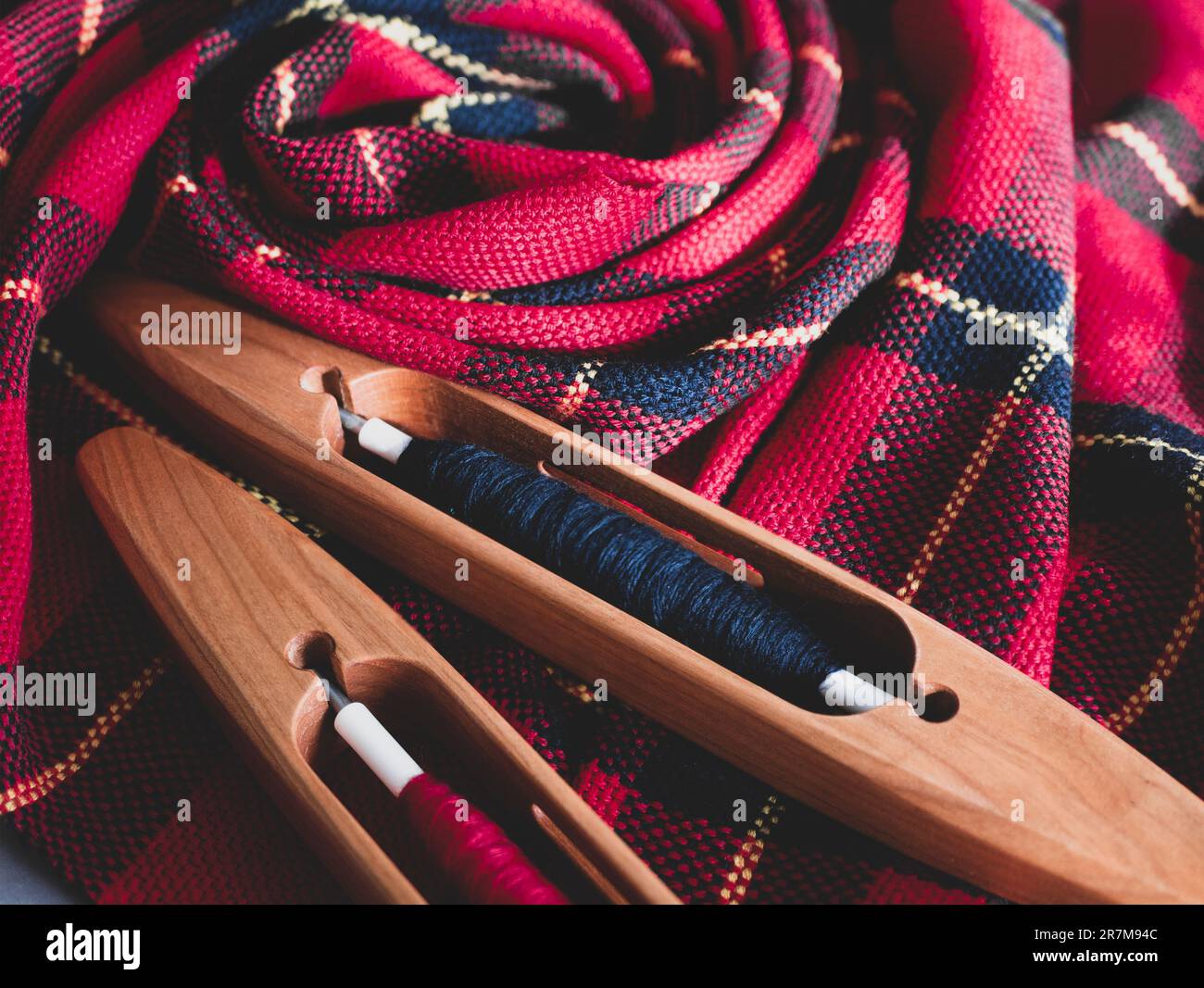 Due navette e tessuto tessuto a mano nei colori rosso e nero, primo piano. Progetto di tessitura pronto, focalizzazione selettiva Foto Stock