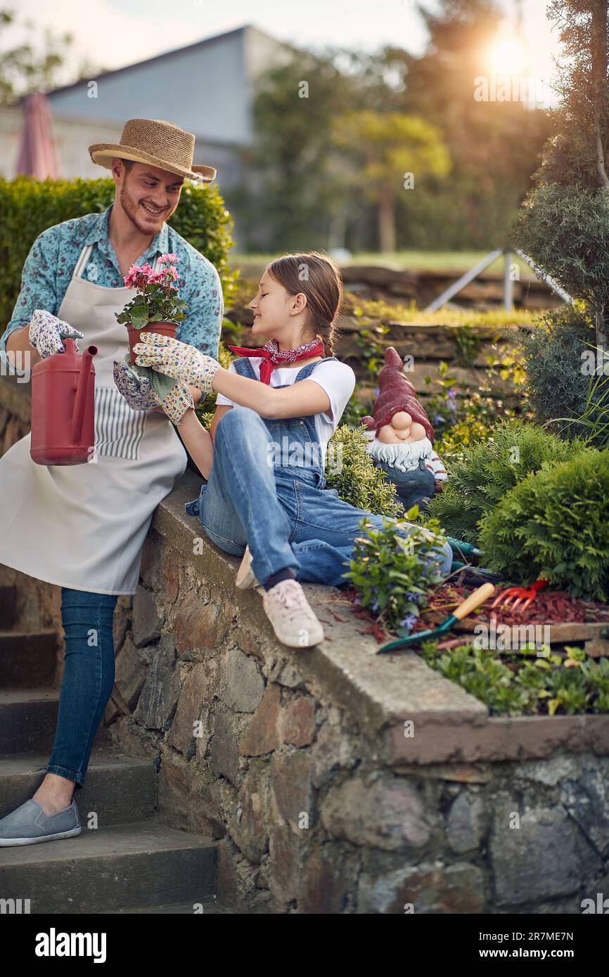 Padre e figlia trovano gioia beatitudine in mezzo alla loro oasi giardino. La loro risata infettiva riempie l'aria mentre si dilettano in compagnia di ciascuno. Foto Stock