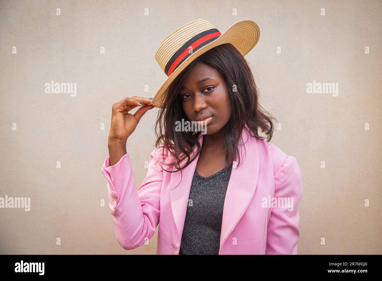 Ritratto di una donna d'affari africana fiduciosa che tocca il cappello elegantemente vestito Foto Stock