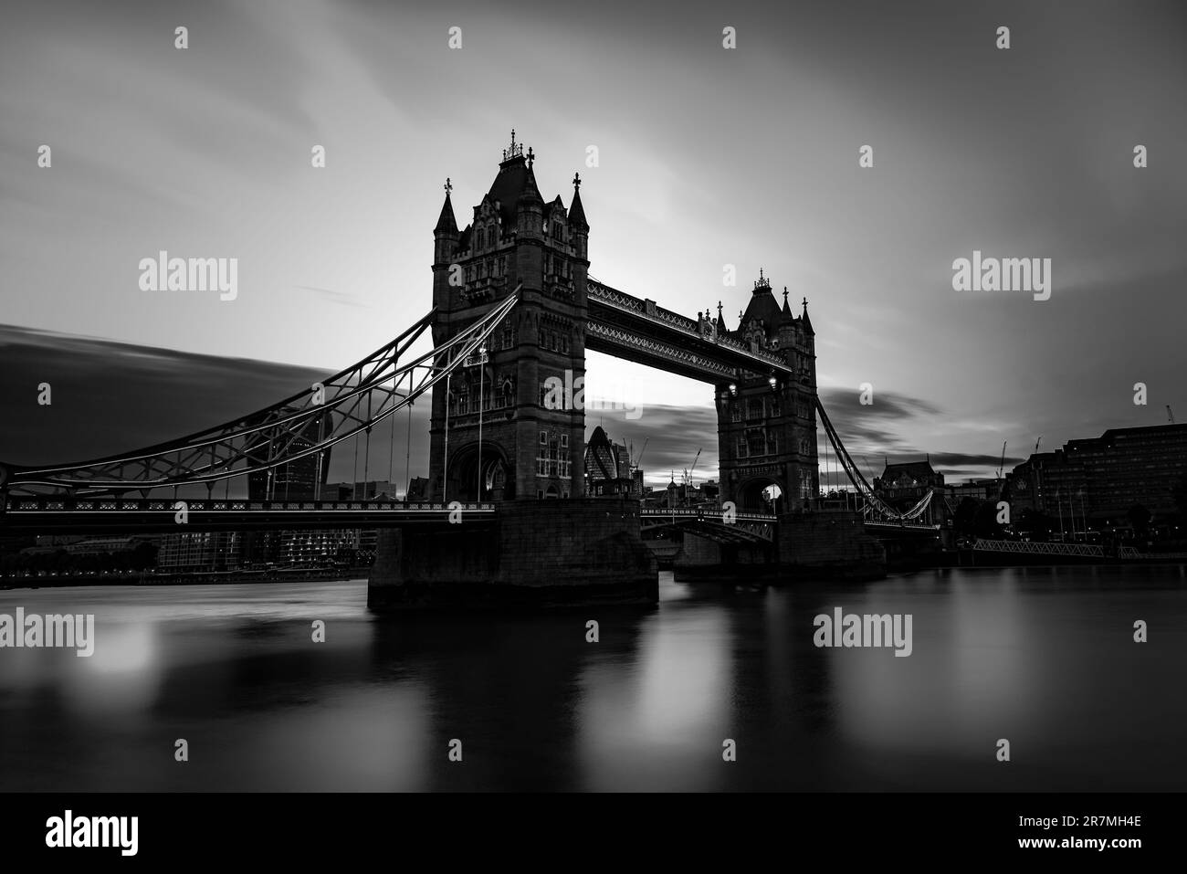 Tower Bridge situato nella città di Londra, Regno Unito, con vista in scala grigia. Calmo fiume Tamigi a lunga esposizione con turismo e vista turistica. Foto Stock