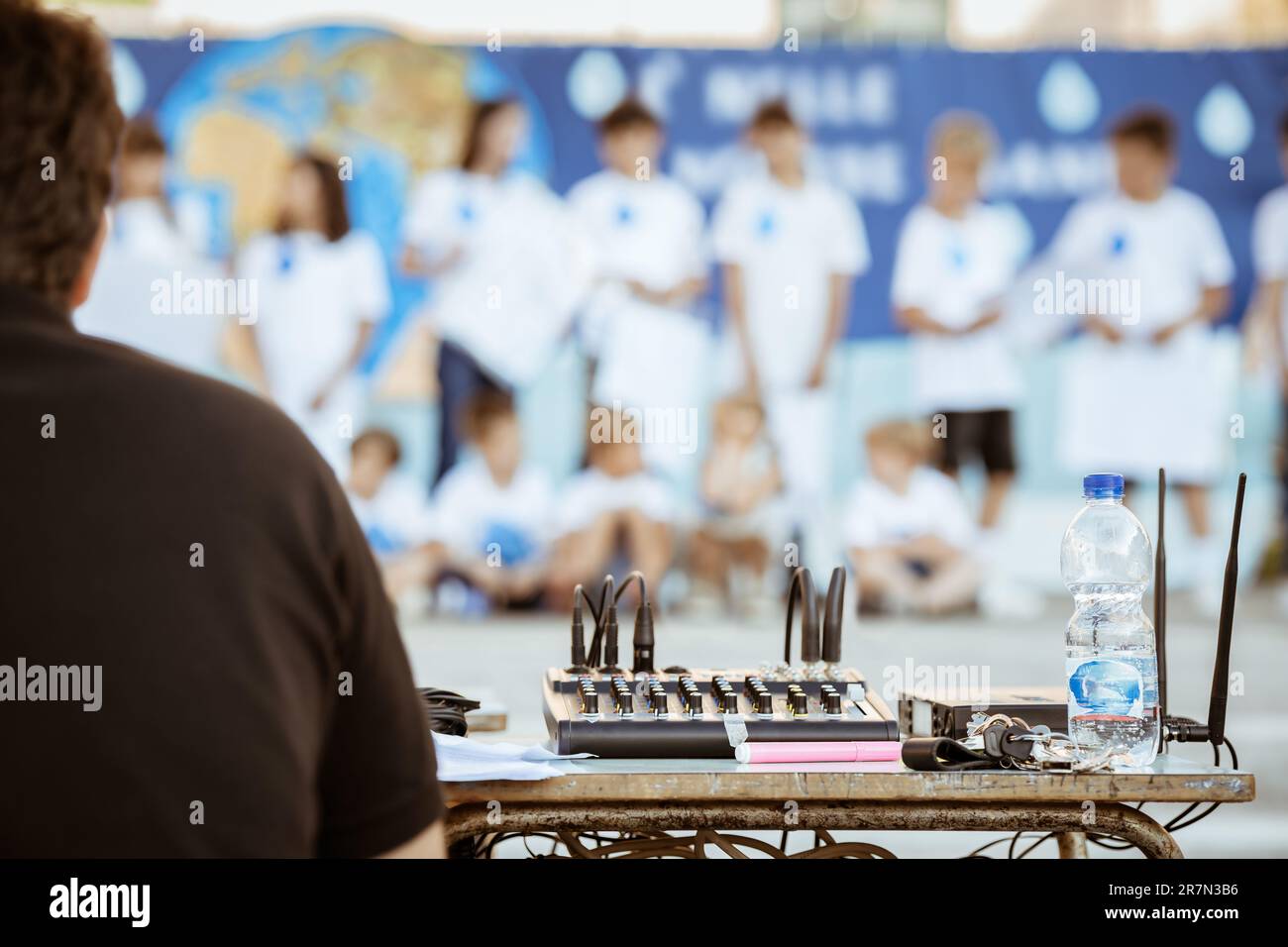 DJ alla console, seduta alla scrivania, concerto all'aperto, laurea per bambini Foto Stock