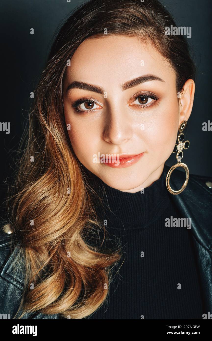 Primo piano ritratto di bella giovane donna con capelli scuri e trucco professionale, posa su sfondo nero Foto Stock