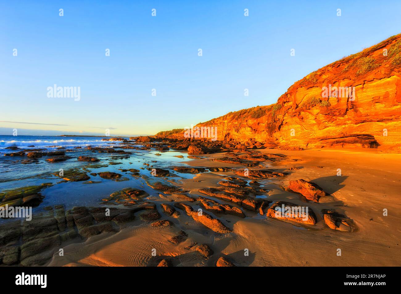 Bassa marea sulla spiaggia di sabbia rocciosa nella spiaggia di Caves sulla costa del Pacifico dell'australia - sunrise Seascape. Foto Stock